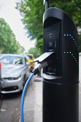 Close-up of Type 1 (Single phase slow charging 13A 3kW) electric car charging point. Power supply plugged into an electric car being charged.