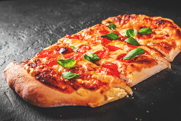 flatbread Pizza with Mozzarella cheese, Tomatoes, pepper, Spices and Fresh Basil. Italian pizza. Pizza Margherita or Margarita on Dark grey black slate background