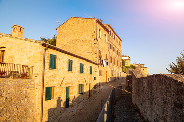 Fototapeta na wymiar Volterra, Tuscany, Italy. August 2020. The walls of the historic village. The warm light of the late afternoon enhances the massive stone wall, at its foot the perimeter path. Tuscan landscape.