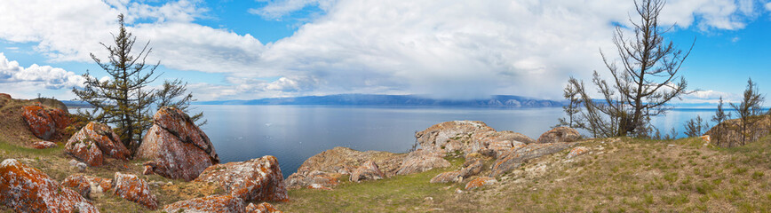 Fototapeta na wymiar Beautiful spring landscape of Baikal Lake. Panoramic view on Budun Cape of Olkhon Island with round red stones on a rocky coast. Natural background. Spring travel and holidays