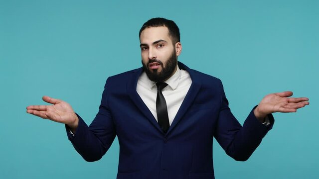 I have no idea! Clueless uncertain doubtful bearded man in black suit raising hands in helpless gesture, embarrassed confused by difficult question. Indoor studio shot isolated on blue background.