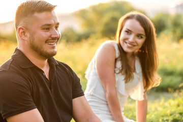 Obraz premium Couple lovers hugging and kissing in park under sunset sky. Love, youth, happiness concept. Summer day
