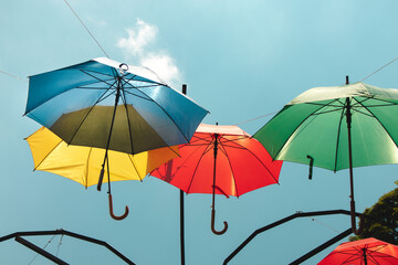 Naklejka na ściany i meble Colorful umbrellas in the sky. Multicolored umbrellas in the sky, creating a summer, art mood on the street