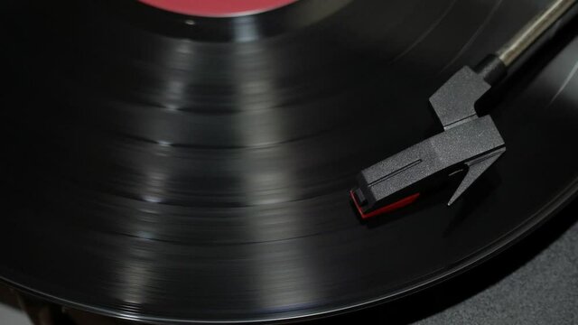 Top view of a needle and a black record. turntable vinyl record spins.