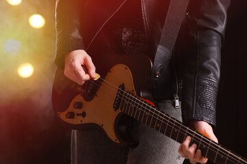 Fototapeta na wymiar Man playing electric guitar on stage, closeup. Rock concert
