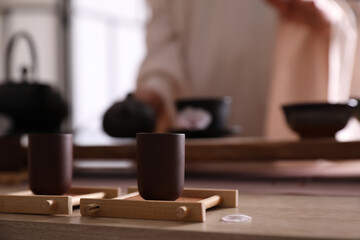 Fototapeta na wymiar Master conducting traditional tea ceremony at table indoors, focus on cup