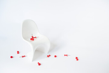 White chair with a red paper pin on a white background. Hemorrhoids concept
