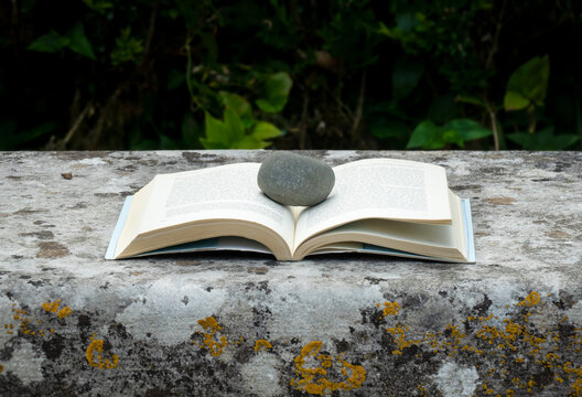 Livro Aberto E Marcado Com Uma Pedra Em Cima De Um Velho  Banco De Jardim,