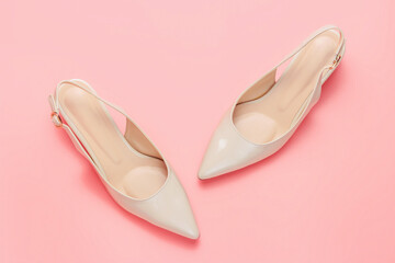 Beige female shoes on pink background close up top view.