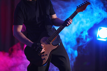 Naklejka na ściany i meble Man playing electric guitar on stage, closeup. Rock music