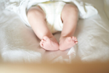 Fototapeta na wymiar Baby legs on white sheet, newborn baby 1 month, care and love with copy space. High quality photo