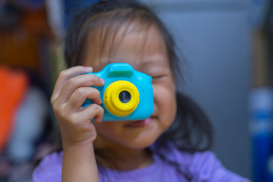 taking pictures of others. Little girl taking picture using toy camera, Photography courses. Camera in hand