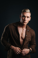 Studio portrait of handsome young man in brown shirt on dark background