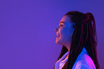 Young woman's portrait on gradient colors studio background in neon. Concept of human emotions.