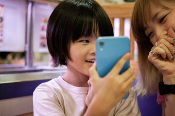 お母さんにスマートフォンを見せる女の子