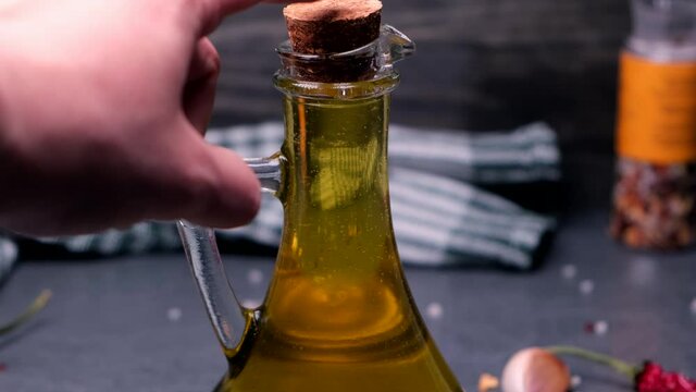 vegetable oil, olive oil, sunflower oil, rapeseed oil, or unrefined almonds are closed in a transparent bottle with a cork
on a dark background.