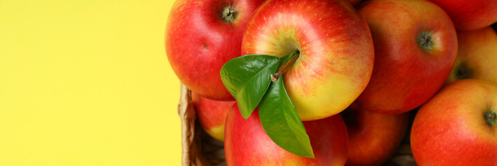 Fototapeta na wymiar Basket with red apples on yellow background