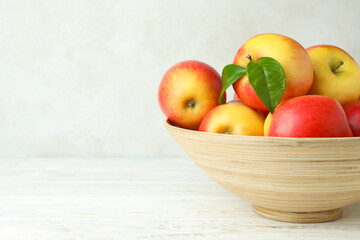 Bowl with red apples on white wooden table