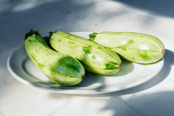 Baby zucchini on a white plate background. over white wooden table.  Organic food.