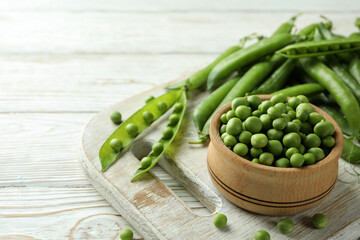 Bowl with pea seeds and fresh pea on wooden background