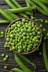 Bowl with fresh pea seeds on wooden background