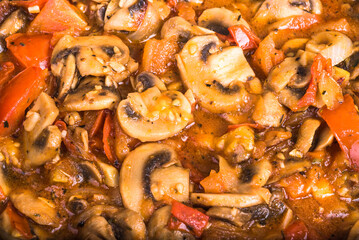 Cooking homemade mushroom sauce of champignons and vegetables, tomatoes and onions. Sauce of cut mushrooms, tomato and onion, close-up, top view. Vegetarian background, mock up