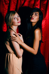 brunette and blond woman together friends on red background, conflict of types