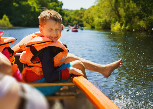 Fun in the water in summer - a boy splashes water on the canoe