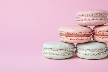 Pile of delicious colorful macarons on pink background, closeup. Space for text