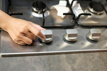 Male hand turning temperature knob of modern oven in kitchen showroom. Buying cooking appliance for...
