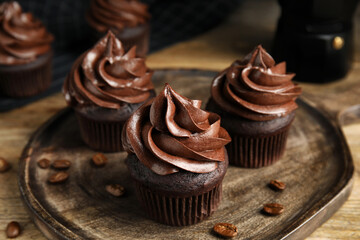 Delicious chocolate cupcakes with cream on wooden table