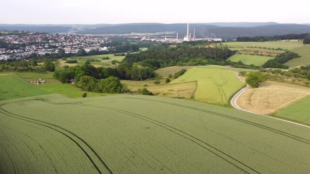 Drohnenaufnahme von Agrarlandschaft und Wohngebiet mit Fabrik.