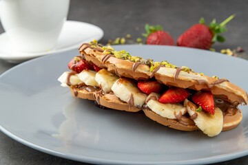 sandwich waffles with banana, strawberry and chocolate and pistachio on top