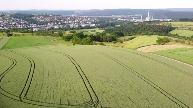 Drohnenaufnahme von Agrarlandschaft und Wohngebiet mit Fabrik.