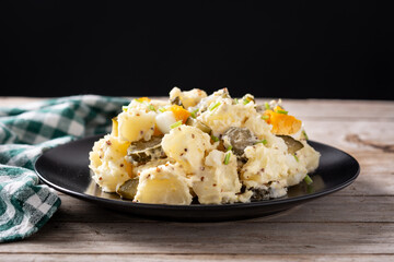 Potato salad with gherkins, egg and mustard on wooden table