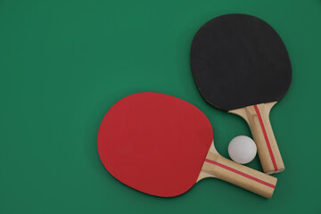 Ping pong rackets and ball on green background, flat lay. Space for text