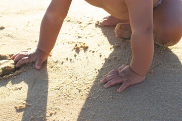 Fototapeta na wymiar Baby boy explore touching sand beach in a sunny day