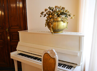 Snow-white grand piano with a golden vase of flowers