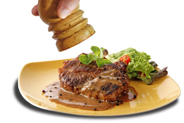 Closeup Black Pepper Steak with the black pepper sauce in the plate isolated on white background....