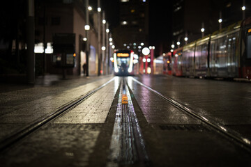 Light rail tracks tram approaching night city lights commuter travel explore public transport