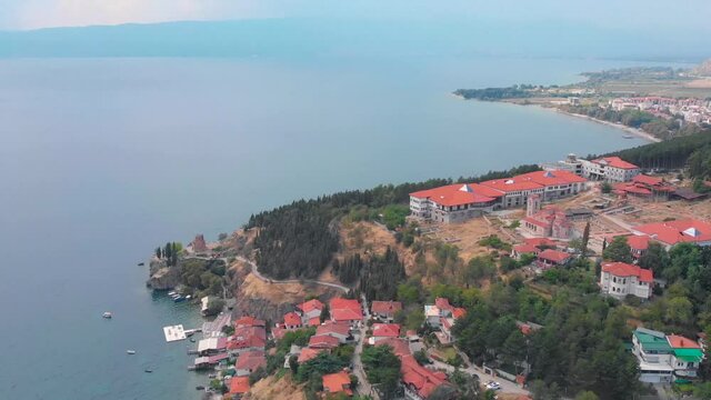 Orthodox church at old town of Ohrid, North Macedonia and village of houses with red roofs. Medieval old gothic architectures look beautiful from above sky with aerial drone 4K 30fps. 
