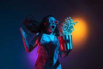Excited in 3D eyewear and with popcorn. Caucasian woman's portrait isolated on blue studio...