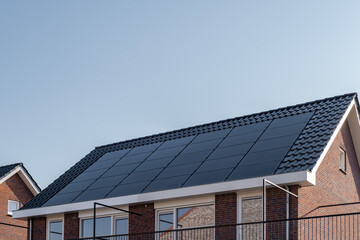 Newly build houses with solar panels attached on the roof against a sunny sky Close up of new building with black solar panels. Zonnepanelen, Zonne energie, Translation: Solar panel, , Sun Energy - obrazy, fototapety, plakaty