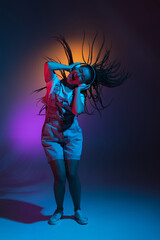 Caucasian young woman's portrait on dark studio background in neon. Concept of human emotions, facial expression.