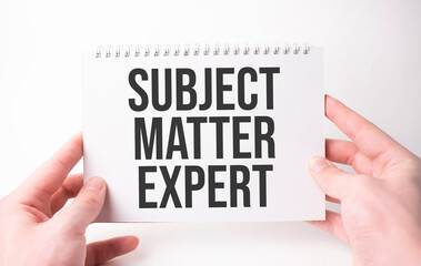 SUBJECT MATTER EXPERT word inscription on white card paper sheet in hands of a man. Black letters on white paper. Business concept.