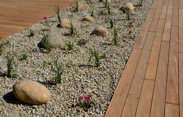 ornamental flowerbed with perennials and stones made of gray granite, mulched pebbles in the city...