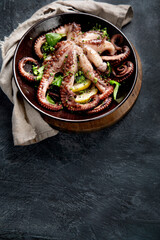 Grilled octopus served with spices and lemon on gray background. Seafood concept.