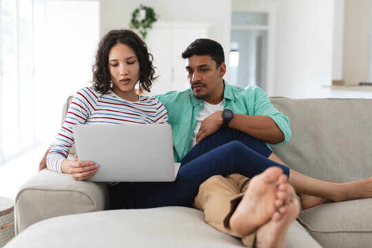 Hispanic couple relaxing on couch using laptop computer together