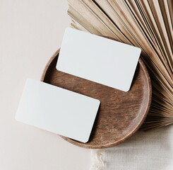 Card mockup with copy space top view, flat lay. Greetings, wedding invitations blank, paper sheet and dry palm leaf on beige background.  