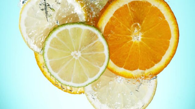 Super slow motion of falling lime, orange and lemon slices into water. Speed ramp effect. Filmed on high speed cinema camera, 1000 fps.